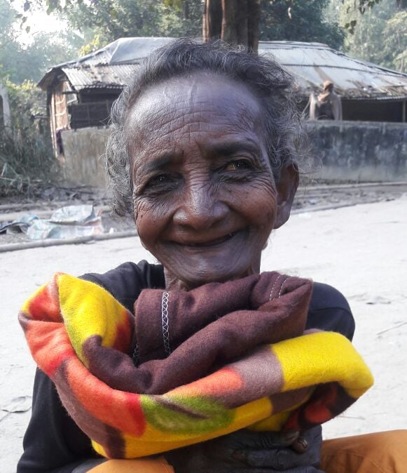 an old woman smiling and holding a blanket