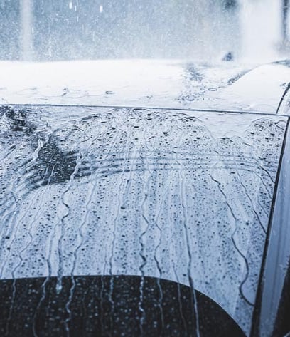 automobilis, kurio priekinis stiklas uždengtas lietumi, bet vanduo varva žemyn dėl hidrofobikos