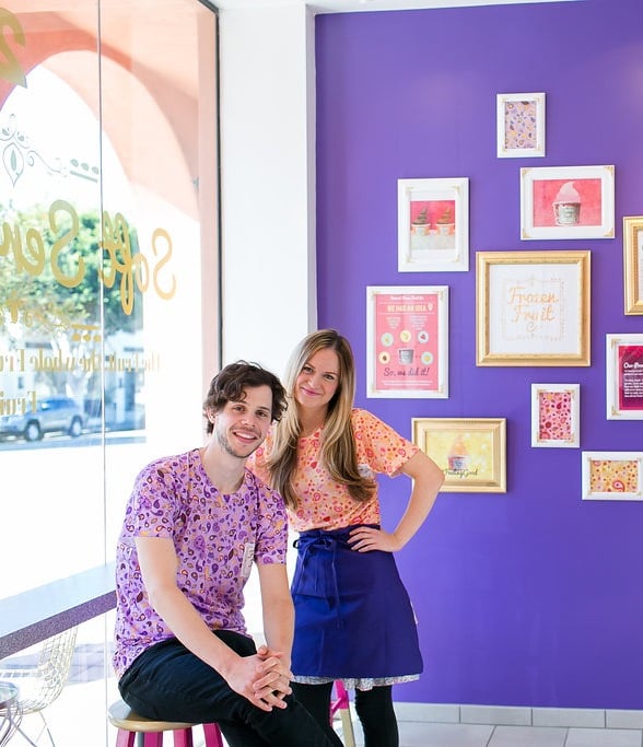 a man and woman standing in front of a purple wall