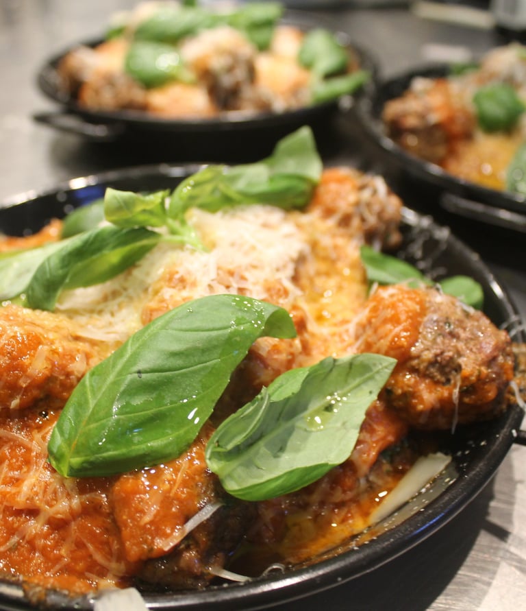 a pan of meatballs with basil sauce