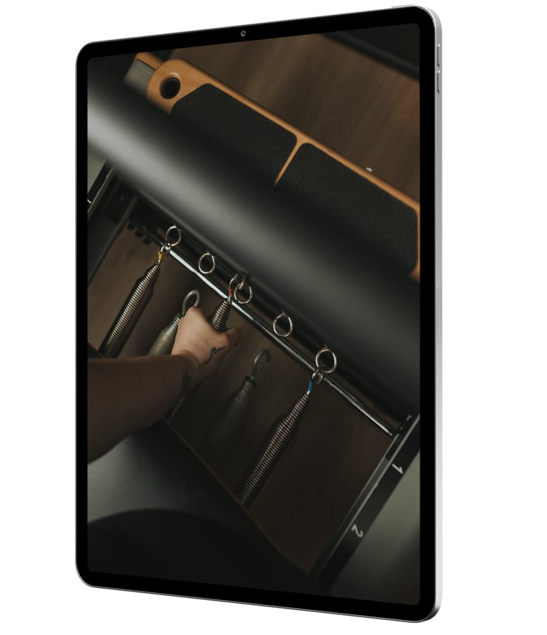 iPad with hand changing Pilates Reformer springs