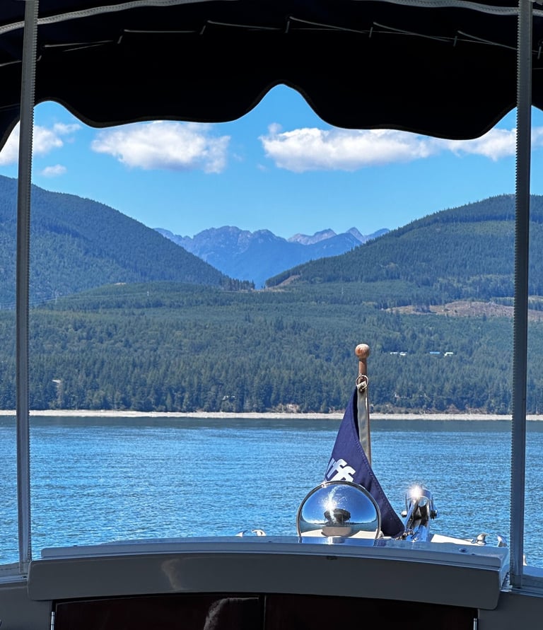 front of boat with flag on pristine water facing majestic mountains
