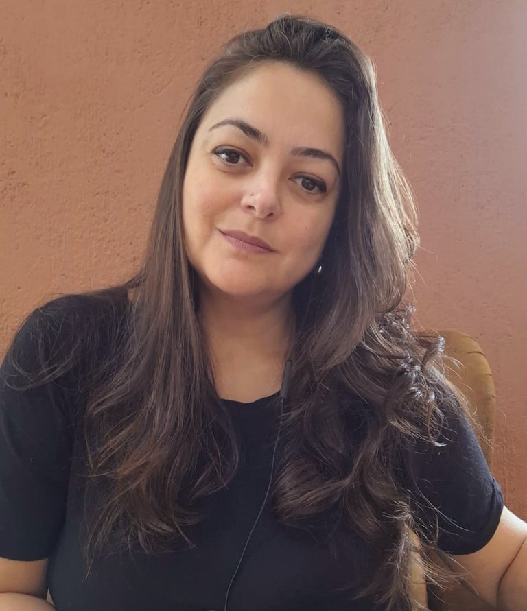 . Psicóloga Marcia Lhamas em seu espaço de atendimento online, cercada por plantas e livros, em atmo