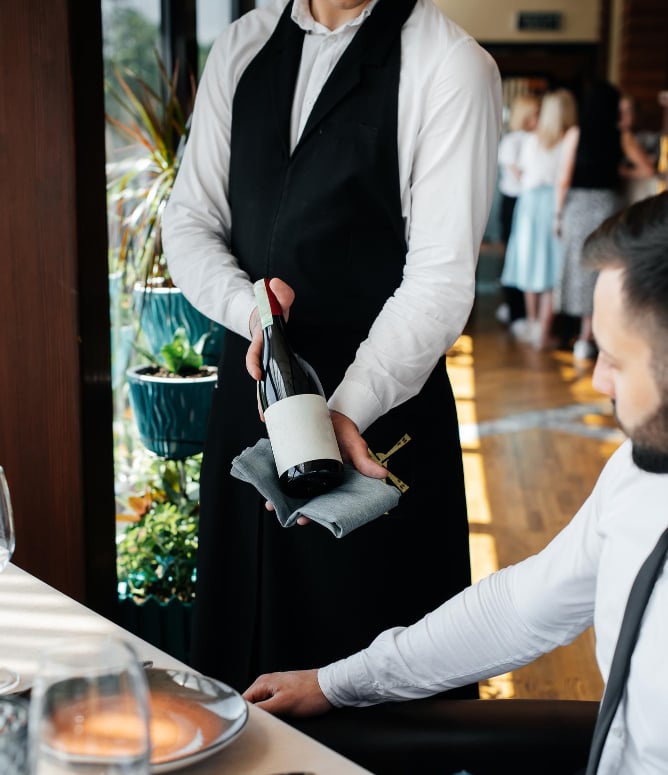 Waiter serving wine in upscale restaurant – hospitality brand experience