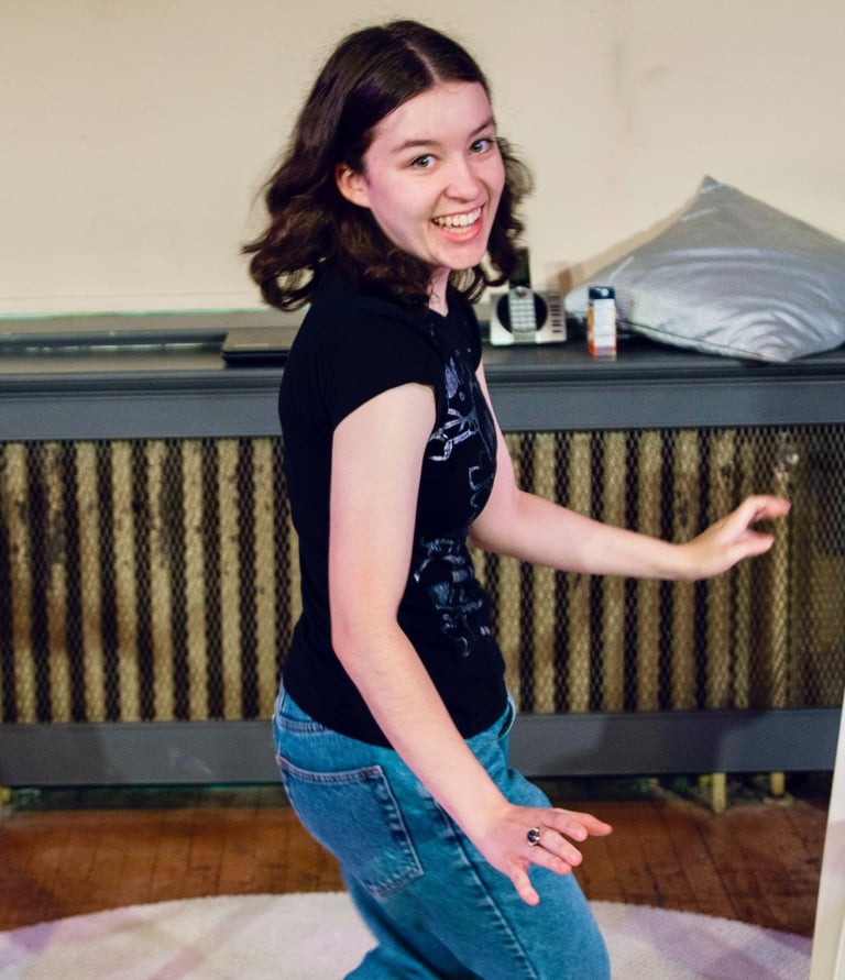 A preteen girl dances giddily as she spins to look at the camera