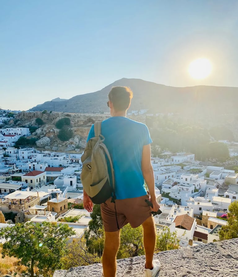 a man standing on a rock ledge overlooking a city