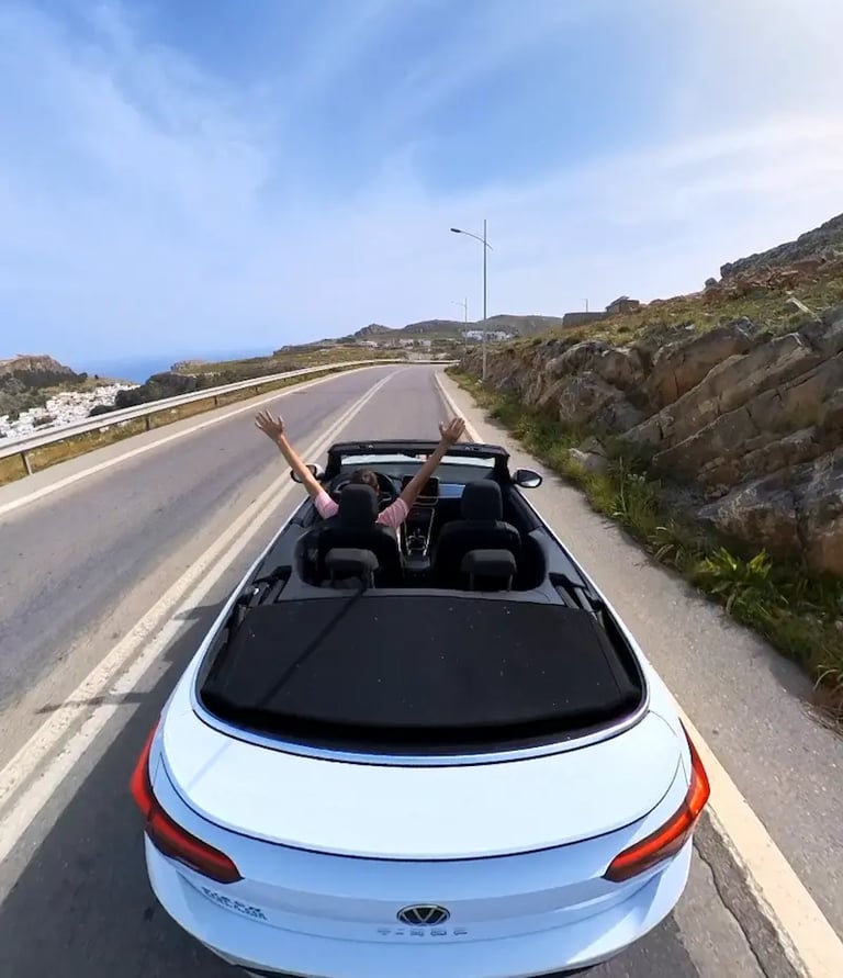 a man driving a convertible car down a road