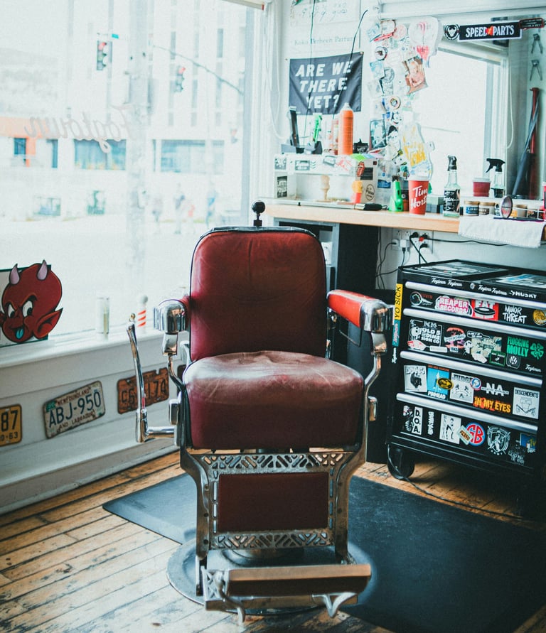 Vintage red leather barber chair in a retro barbershop with punk rock stickers and license plates.