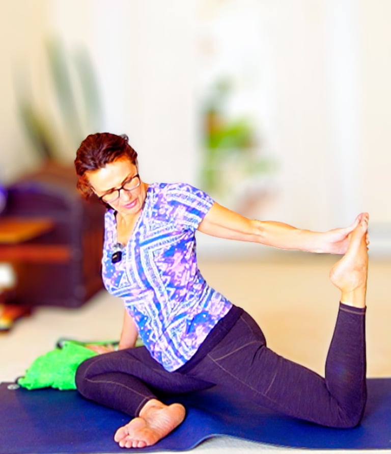 Woman practicing the King Pigeon yoga pose on a blue mat for flexibility and core strength.