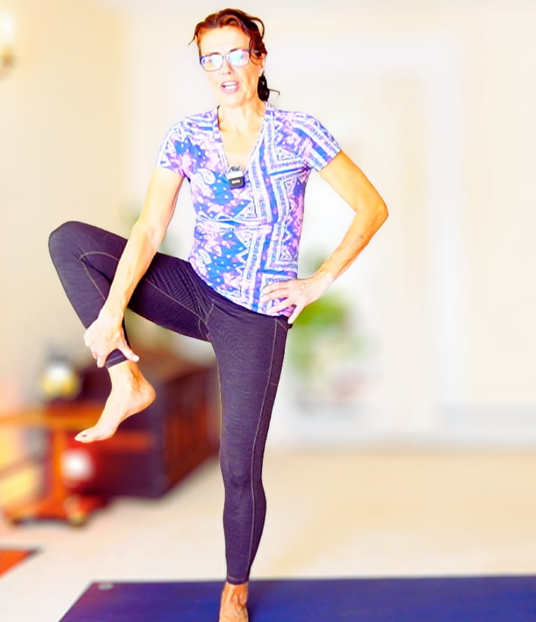 A woman in a yoga studio performing a balance yoga tree exercise 