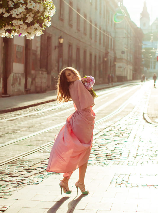 a sugar mommy in a pink dress is dancing on a brick road in Melbourne.