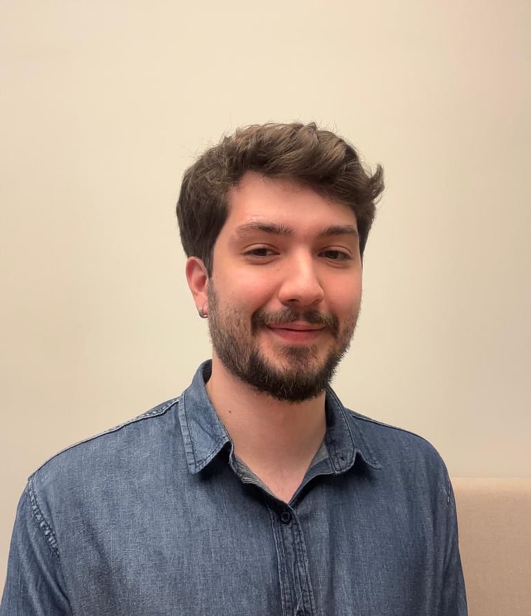 Foto do psicólogo do peito pra cima. Um homem branco com barba e cabelos castanhos, de camisa azul.