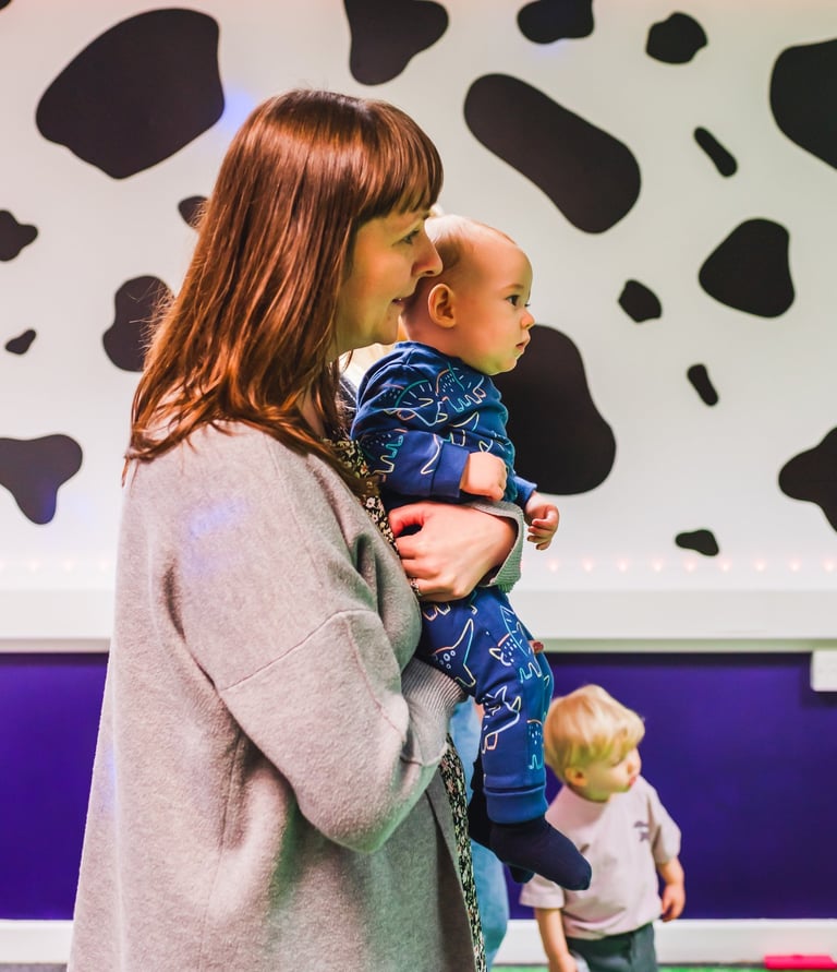 Mum standing, holding her baby in baby moo.
