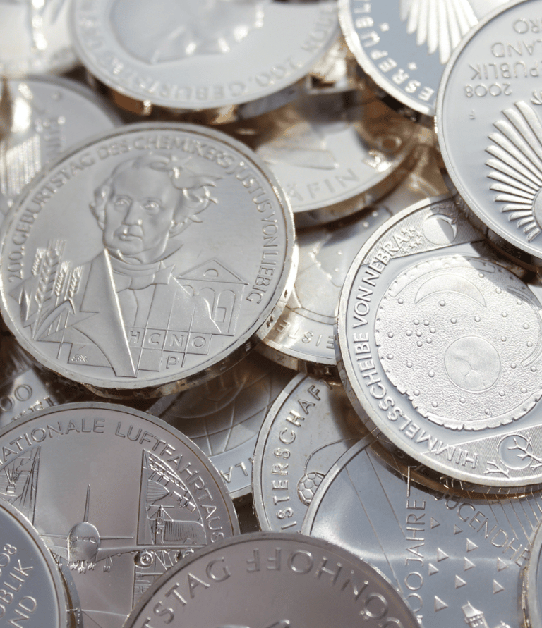 a pile of coins with a person holding a coin