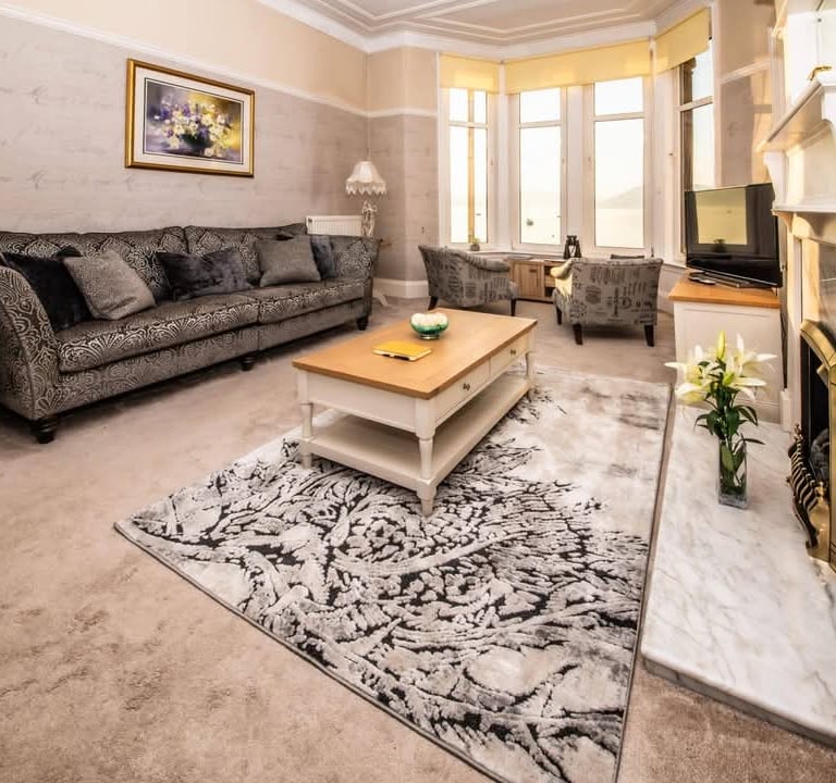 The spacious living room at Gourock Seaview Holiday Let with a couch, armchairs and a fireplace