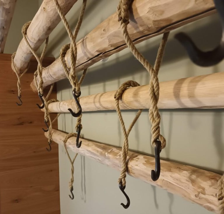 geschmiedete Kleiderhaken an Tauen an einer Holzgarderobe