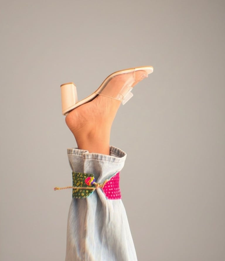 a person's feet in a dress shirt and heels