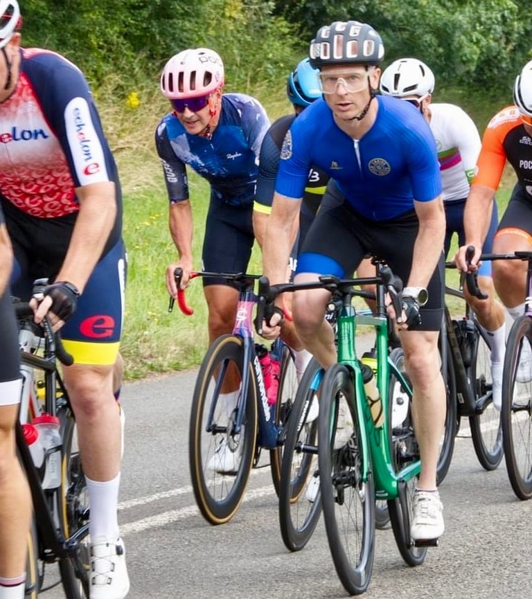 a group of cyclists riding bikes on a road