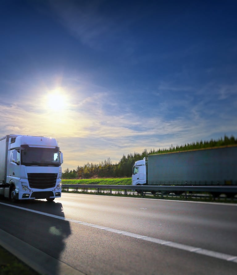 a truck driving down a highway with a bright sun shining on the road