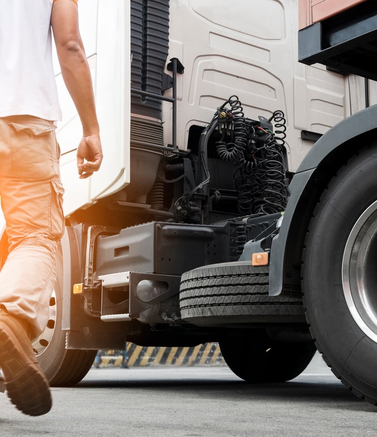 a man walking away from a truck with a large tire