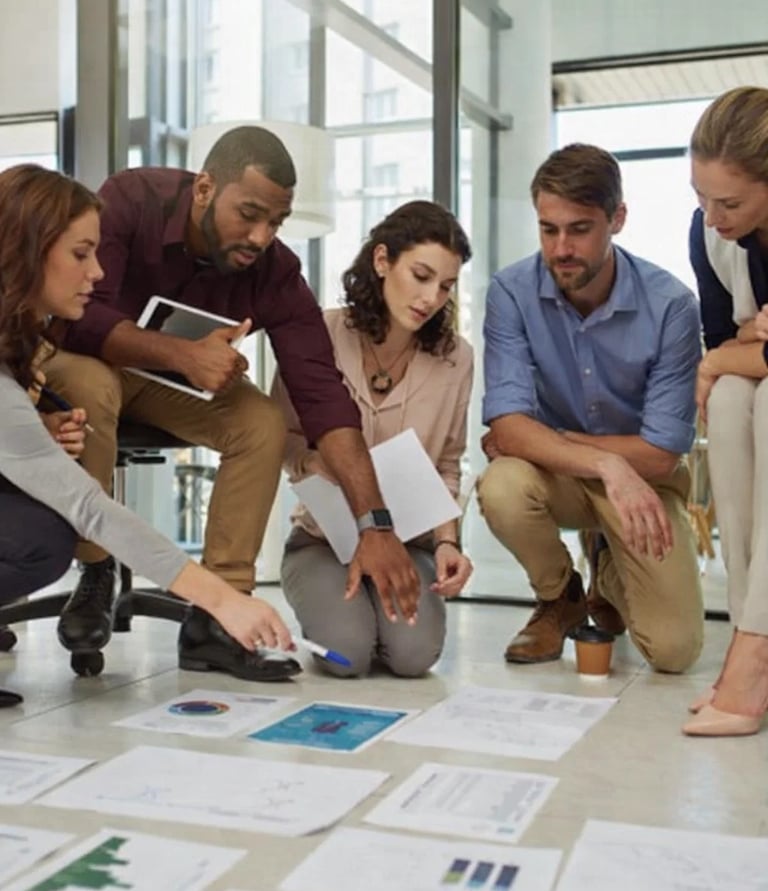 Diverse business team collaborating on floor with data charts and marketing reports.