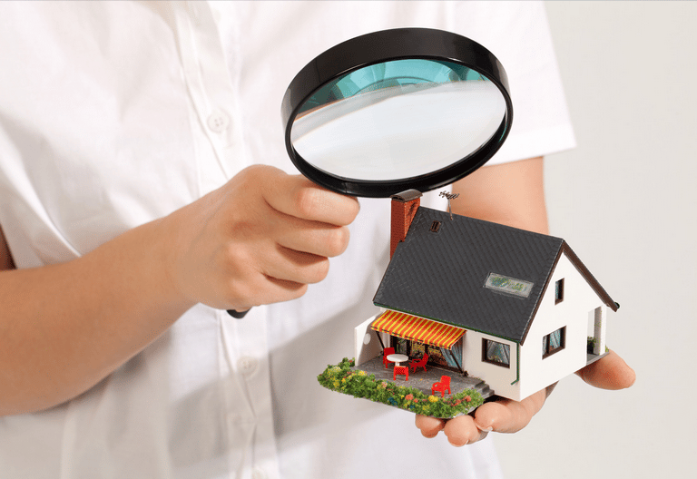a person holding a magnifying magnifying a house