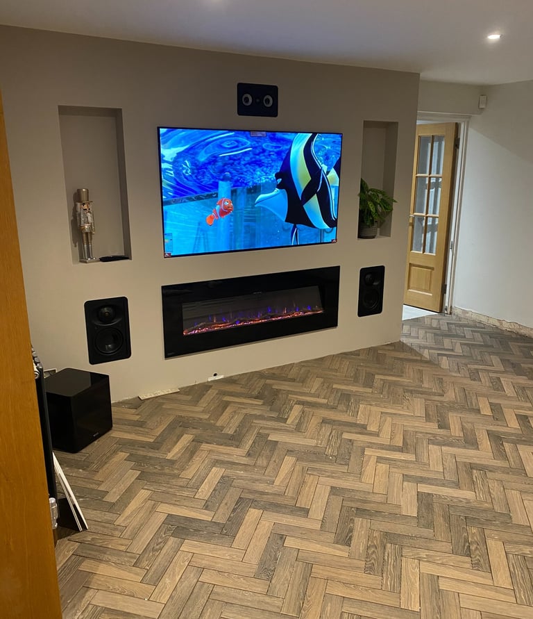 Living room with wooden floors and off white walls. A TV and fireplace are built into the wall.