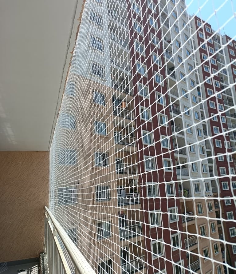 Wide shot of a modern apartment balcony secured with Arjilli Safety Nets against pigeons.