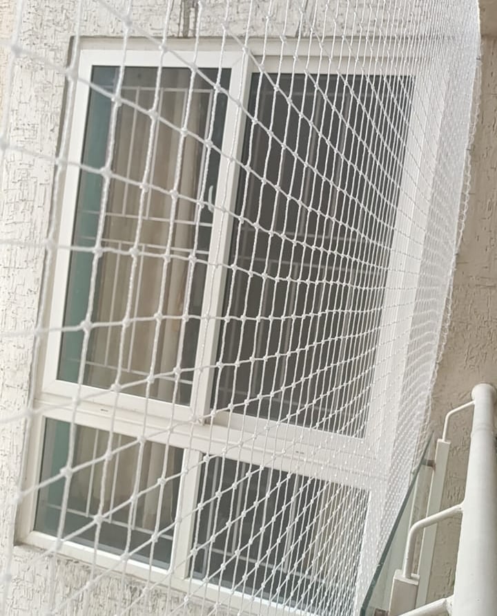 A panoramic view of pigeon nets installed across multiple balconies in a busy Lower Parel neighborho