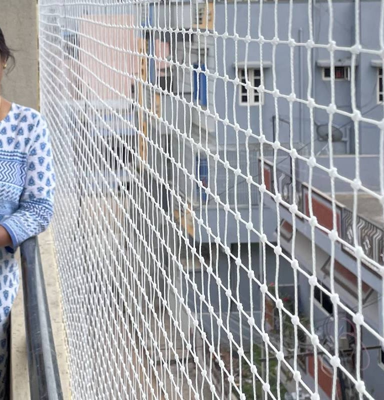 Close-up of a securely fitted safety net protecting a balcony from pigeons in a busy Bombay neighbor