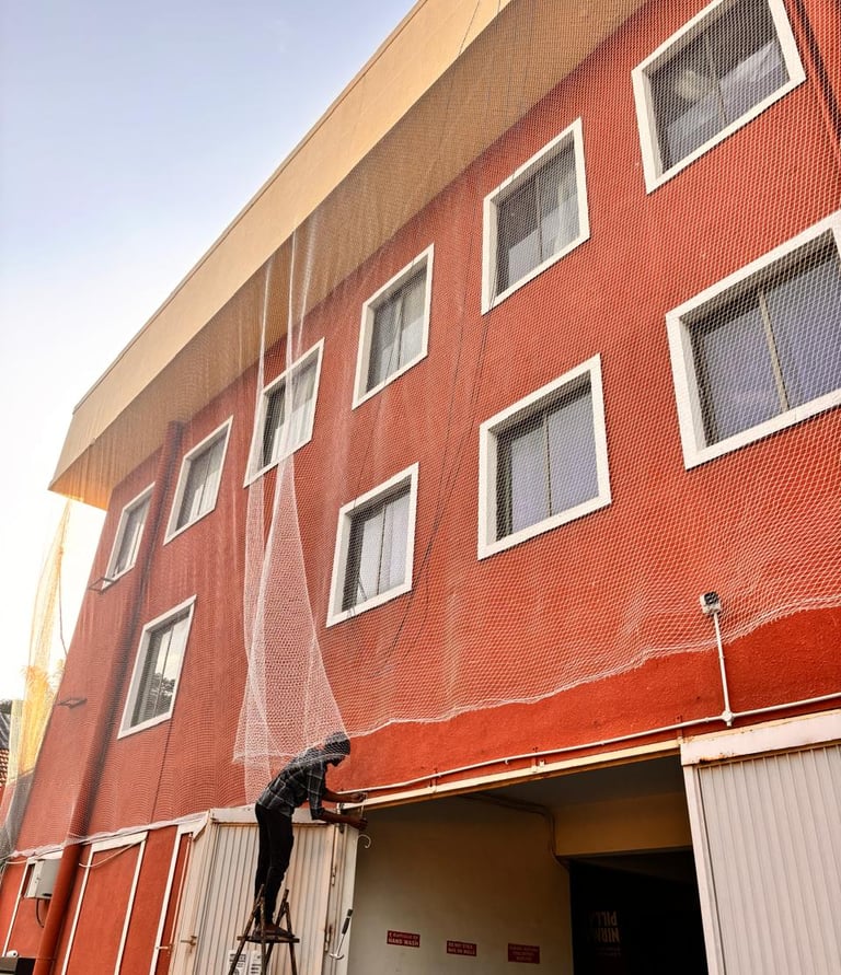 An Arjilli Safety Nets team member carefully installing a sturdy pigeon net on a Mumbai balcony unde