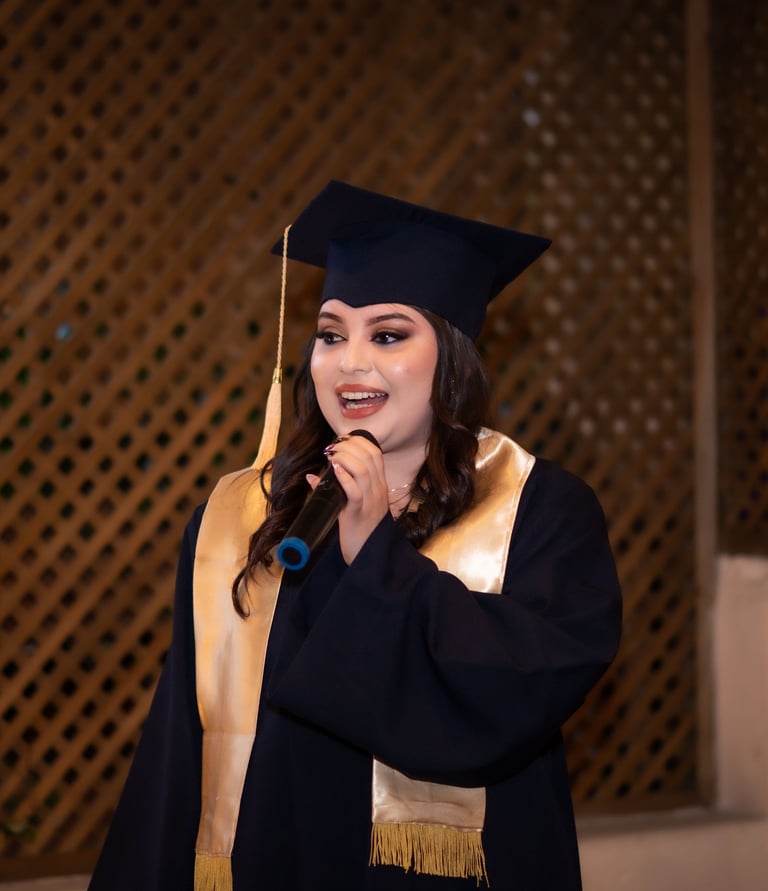 Una graduada sonriente con toga y birrete negros dando un discurso frente a un micrófono .