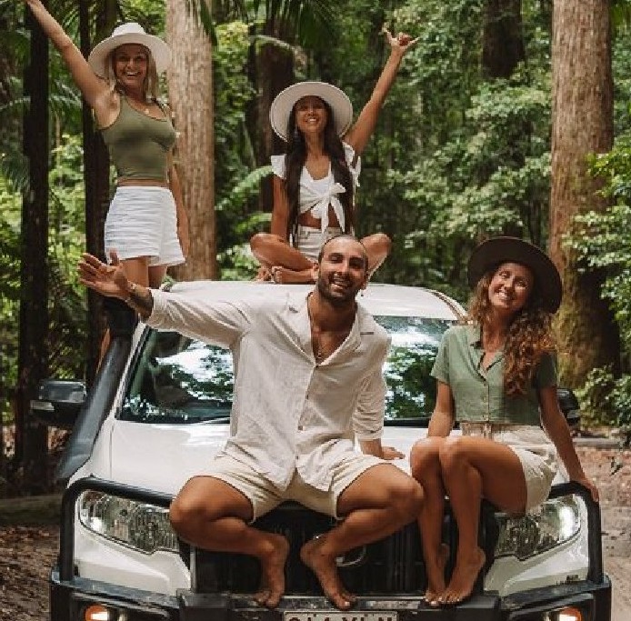 A group of friends on a tropical 4x4 road trip adventure in a lush green rainforest.