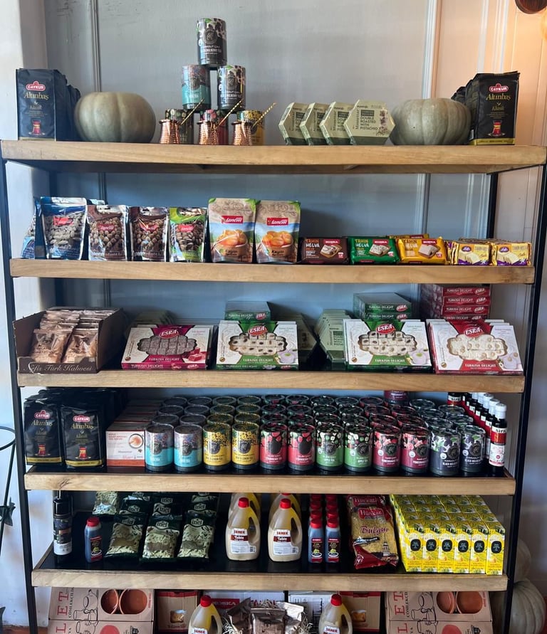 Wooden grocery shelves stocked with Turkish tea, delight, helva, and spices for sale.