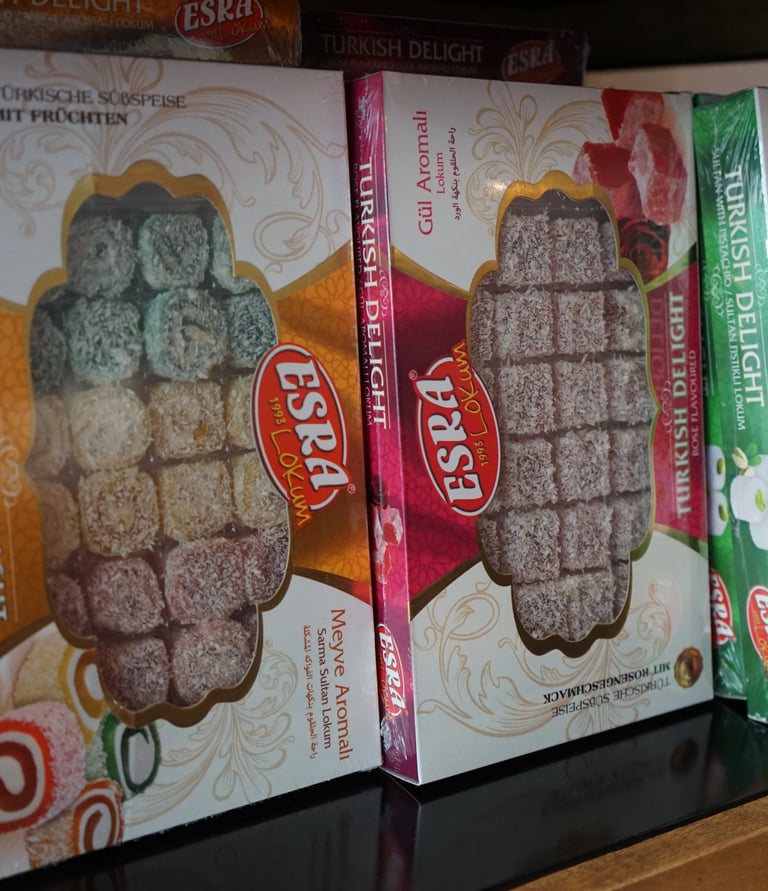 Boxes of Esra brand Turkish Delight in rose, fruit, and pistachio flavors on a shelf.