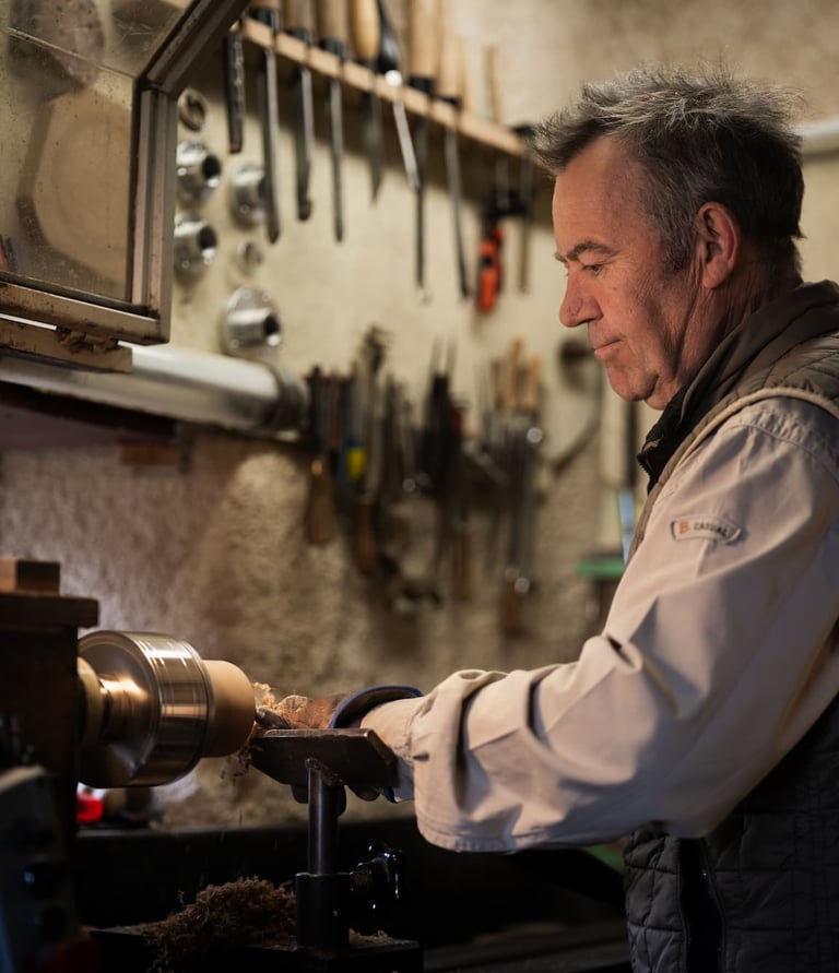 Artisan travaillant soigneusement une pièce de bois sur un tour à bois dans son atelier. L'atmosphèr