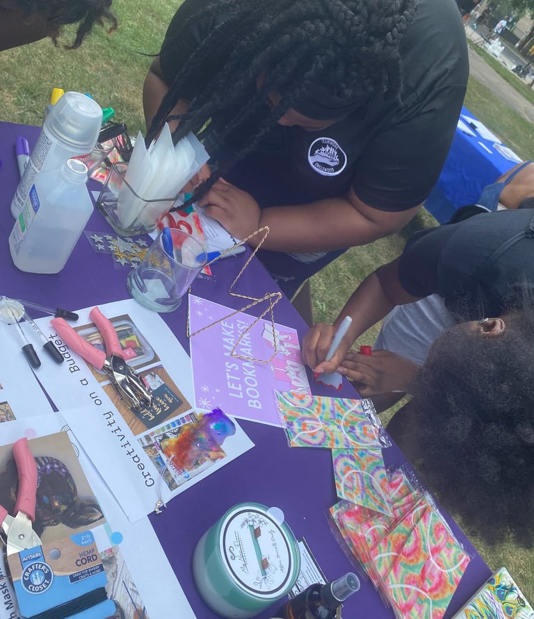 two girls at a table making a book mark out of recycled material