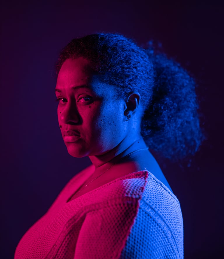 A woman's dramatic profile portrait with vibrant pink and blue neon lighting in a studio.
