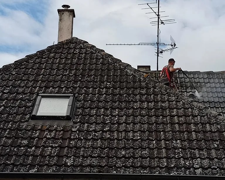 Couvreur réalisant un nettoyage en profondeur d’une toiture envahie par les mousses à Montbéliard, pour restaurer l’étanchéit