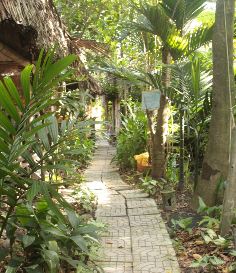 Traditional thatched-roof cottages surrounded by lush gardens at Saigon Garden Homestay.