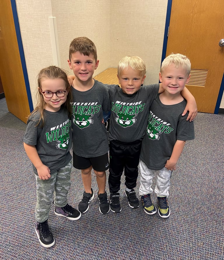 four young children standing in a hallway with their arms around each other
