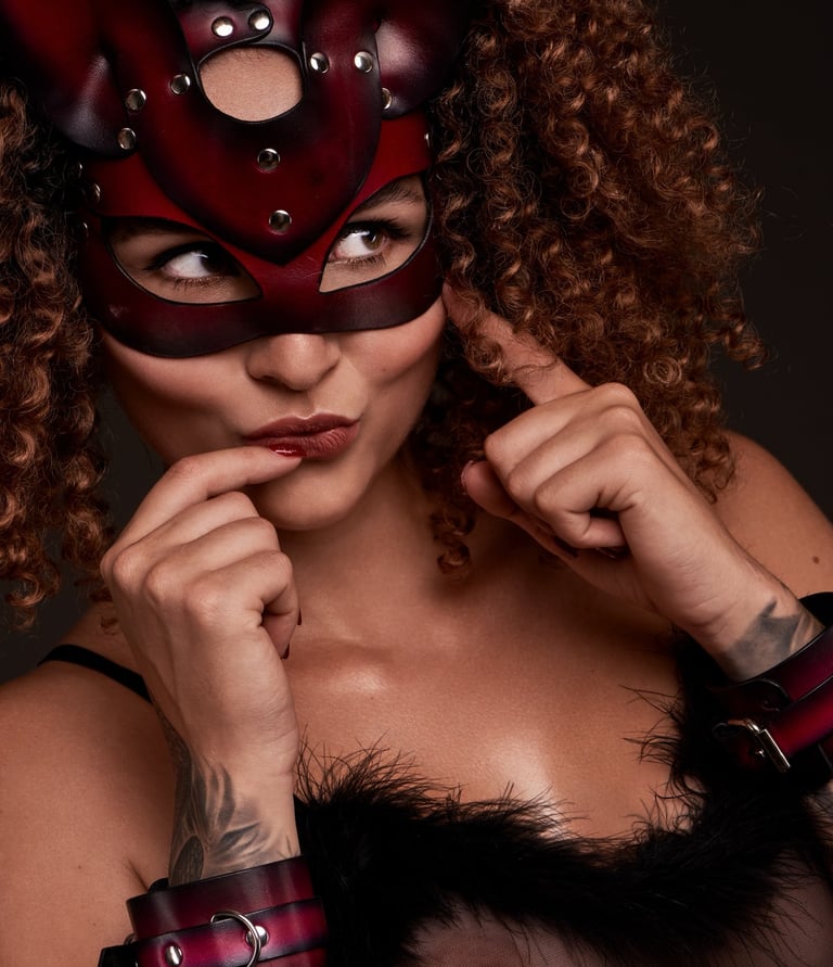 a woman in a red cat mask and with leather restraints