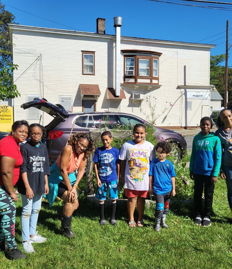 8 individuals gathered to take a picture after volunteering at a community garden