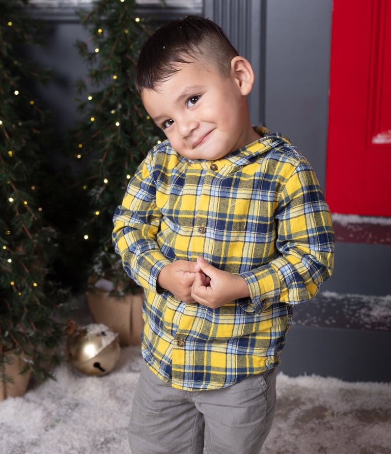un niño pequeño sonriendo a la cámara en un set de fotos navideño