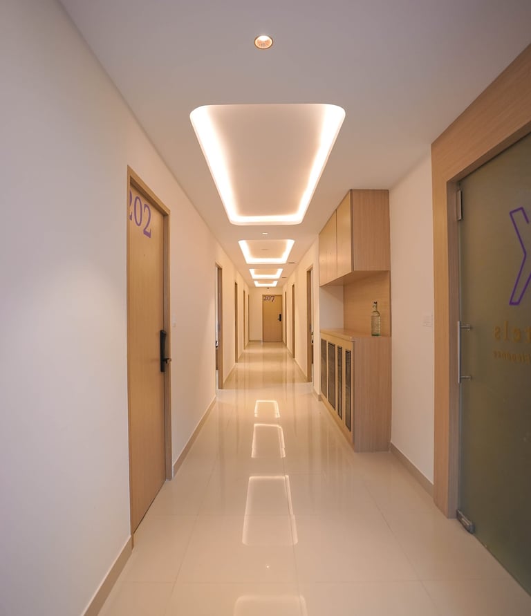 Modern hotel corridor with sleek wooden doors, recessed ceiling lighting, and polished tile floors.