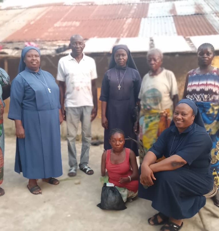 Catholic nuns in blue habits visit a local family in a rural African community to provide support.