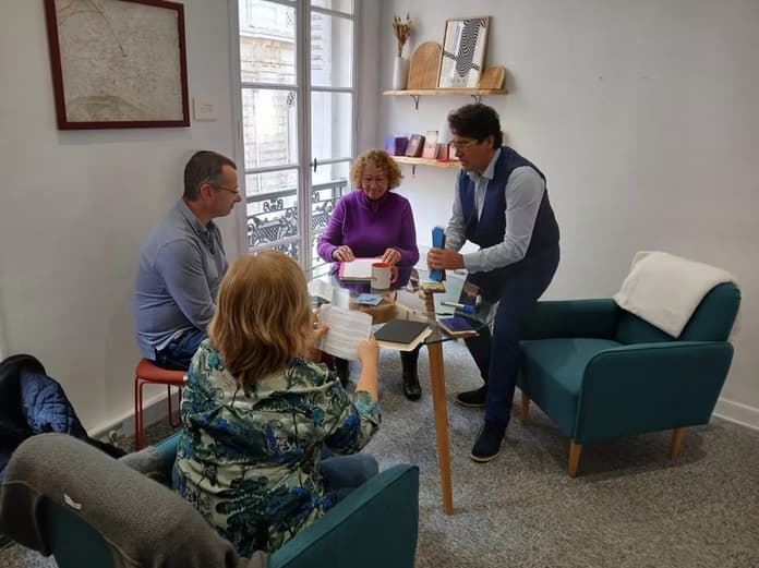 Olivier Paris debout devant trois personnes assises autour d'une table