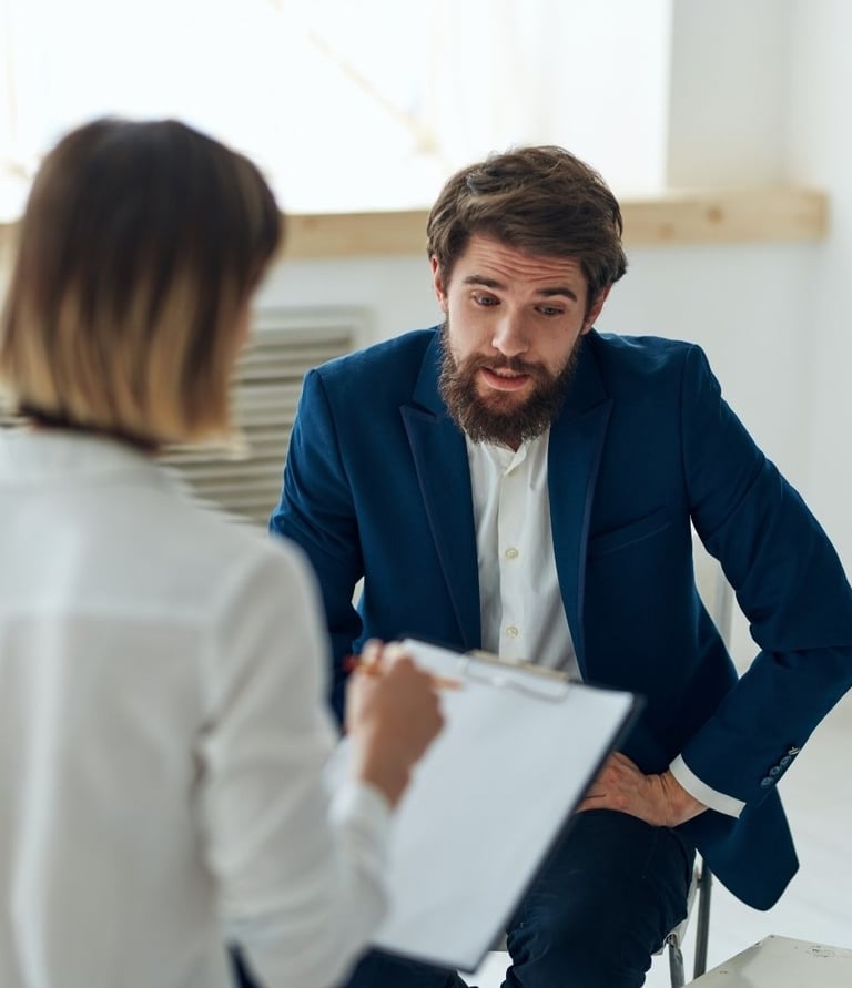 a man and woman in business attire sitting in a meeting room