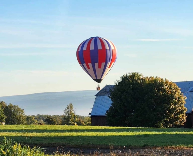 a hot air balloon in the sky over a barn