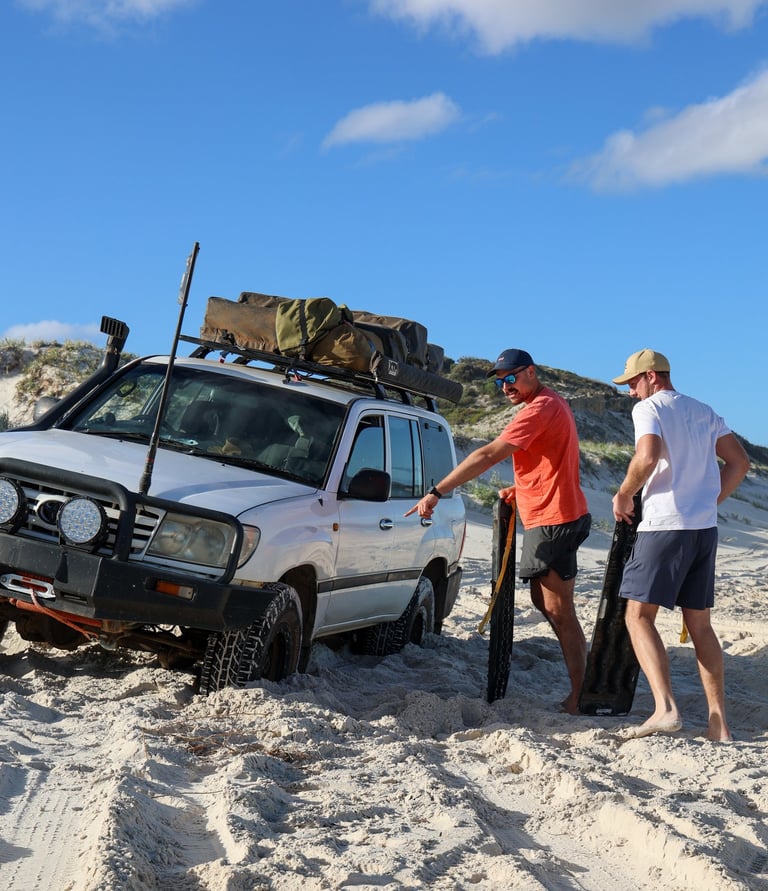 4x4 voertuig wordt uitgegraven met recovery boards in het zand van West Australië